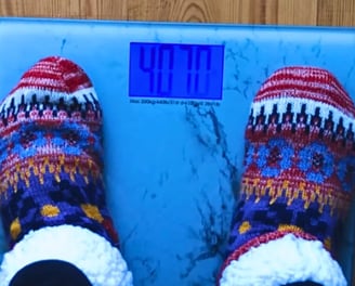 Feet standing on a weight scale representing weight loss moderation journey