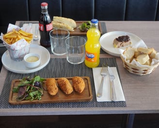 Table setting with a variety of foods including crispy breaded croquettes with salad, golden French