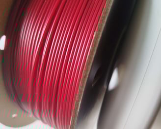 Spool of dark red 3D printing filament on AMS