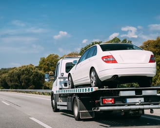 a white car is being towed on a flatbed