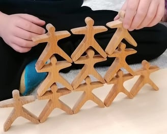 Kind baut Holzpüppchen-Pyramide