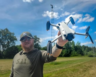 Dronepiloot toont DJI Mini 4 Pro drone in open veld tijdens voorbereidingen voor luchtinspectie op locatie