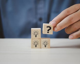 a person holding a wooden block with question mark