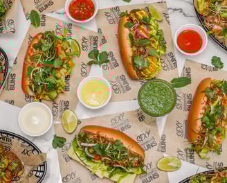 a flatlay of lots of sexy buns on a table, garlic bread, sauces all very colourful