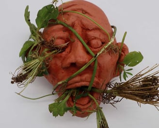 Sculpted face up close with plants 