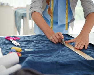 Señora marcando un trozo de tela para realizar un corte y crear una prenda de ropa