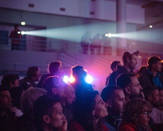 Public captivé devant une projection, éclairé par des faisceaux lumineux en ambiance immersive