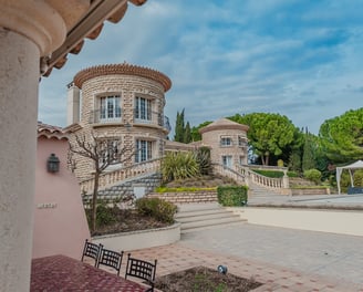 Villa de luxe en pierre avec tours, escalier élégant et jardin arboré