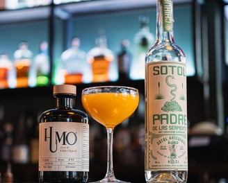 Cocktail mexicain à base de liqueur Humo au chipotle et Sotol Padre, sur fond de bar moderne