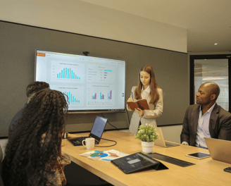 Team member presenting data analytics insights on a large screen in a conference room.