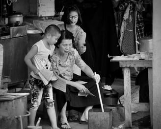 Asian family with roadside stall stirring the ashes in a tin