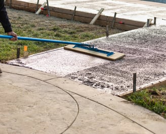 a person using a broom to clean a sidewalk