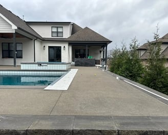 a pool with a concrete pool and a concrete patio