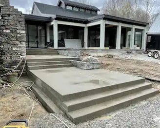 a house with a large concrete patio with steps leading up to a large house