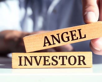 a person holding a wooden block with the words angel investor