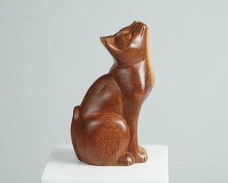 a wooden cat statue of a cat sitting sculpture on a pedestal