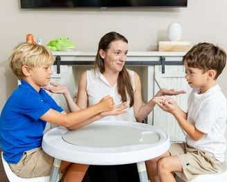 A photo of the therapist watching two boys playing scissors, paper, rock 