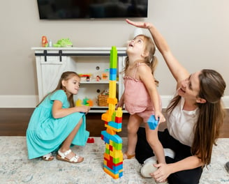 Therapist building a block tower with two sisters