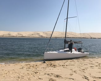 a man standing on a beach with a sailboat