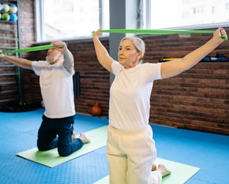 elderly adult male and female exercising with bands