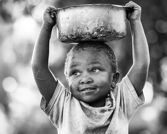 A smiling African child carrying a water container