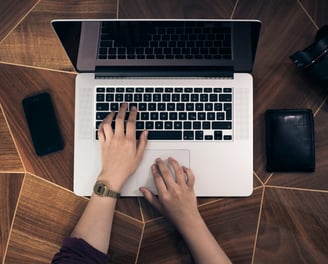 Top down view of a person working on a MacBook at a desk.