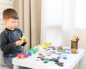 a young boy sitting at a table with a cupcake