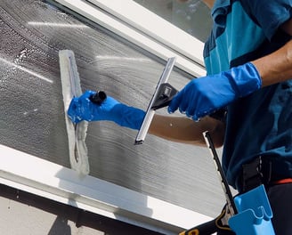 a man in blue gloves and gloves is cleaning a window