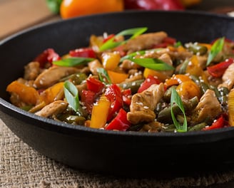 Prato de frango xadrez com pimentões, cenoura, cebola e ervilhas, decorado com cebolinha e sementes 