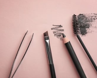 a few brushes and a brush are on a pink surface