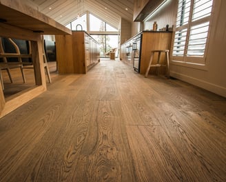 Kitchen and dining area features custom hardwood floors and cabinetry, warm, modern space.