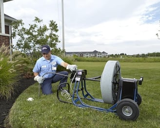 A man in a blue shirt is holding a hose