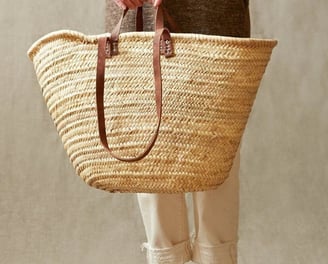 a woman holding a basket weaved basket bag