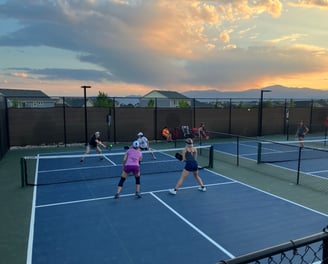 Adults playing competitive pickleball on outdoor courts during a pickleball coaching session.
