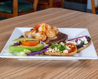 Surf and turf plate with shrimp, grilled steak, sopes and fresh salad served at Kraken Mar y Tierra