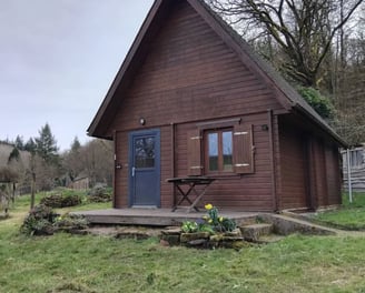 Wooden lodge nestled in nature at Les Vieilles Forges campsite in Brittany, featuring a private deck