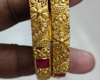 a pair of gold plated bangles with emerald stones