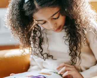 A young girl reading a children's picture book.