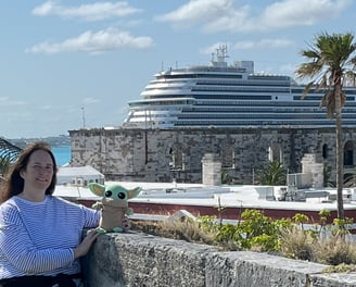 Woman standing against a small wall with Cruise Ship in the background