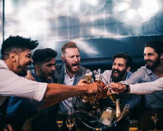 Group of men celebrating with drinks on a bachelor party bus crawl, enjoying a lively and fun night out.