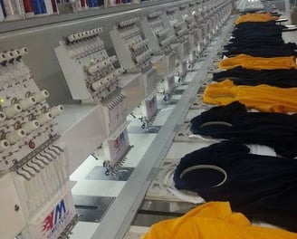 Technician operating embroidery machines for custom tactical patches at Zestlet.