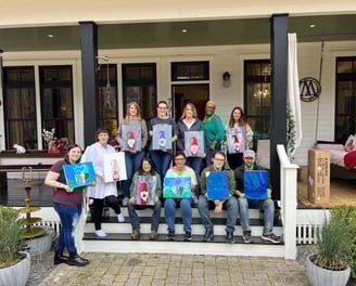 a group of people holding up their paintings