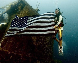 a scuba diver with a flag on a rock formation