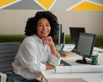 a woman sitting at a desk with a laptop and a computer