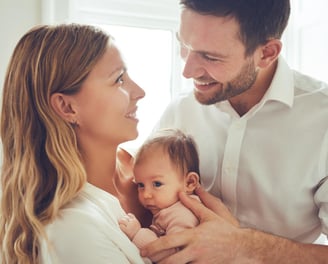 a man and woman holding a baby in a white shirt