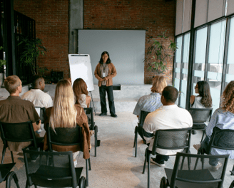 a woman in a brown jacket is standing in front of a group of people