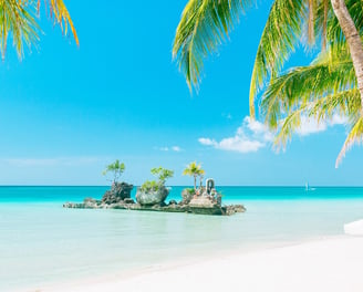 The famous rock formation in Boracay Island with white sand and tall palm trees, with clear blue sky