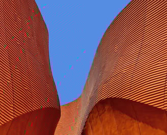 Bâtiment orangé et courbe sur un ciel bleu