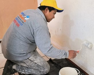"Técnico de Serviacabados reparando una pared con humedad en una vivienda de Quito, especializado en