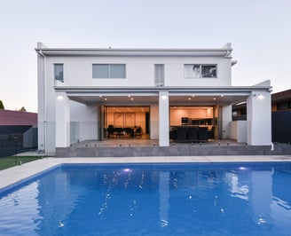 modern white home with outdoor entertainment and pool in foreground